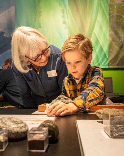 Een medewerkster van het museum die een jongetje helpt